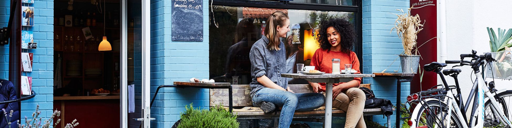 Vor einem Cafè zwei Frauen mit Stevens Fahrrädern